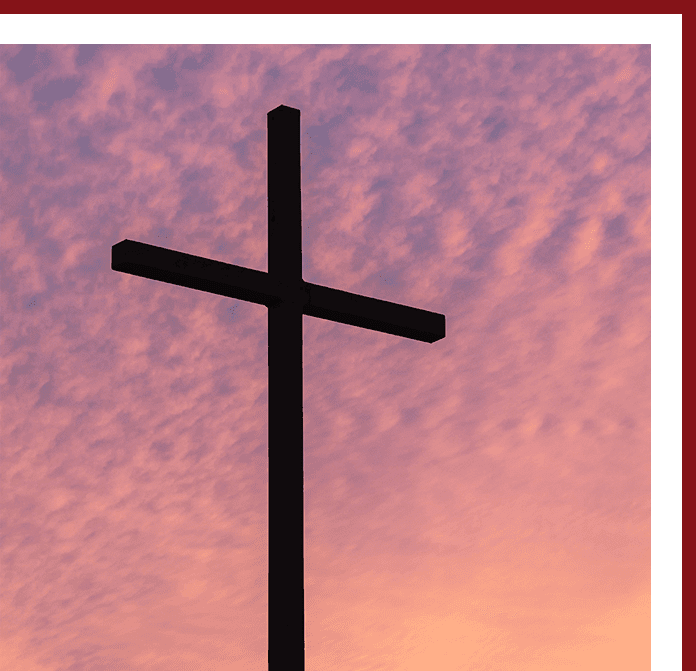 A cross is shown against the sky at sunset.